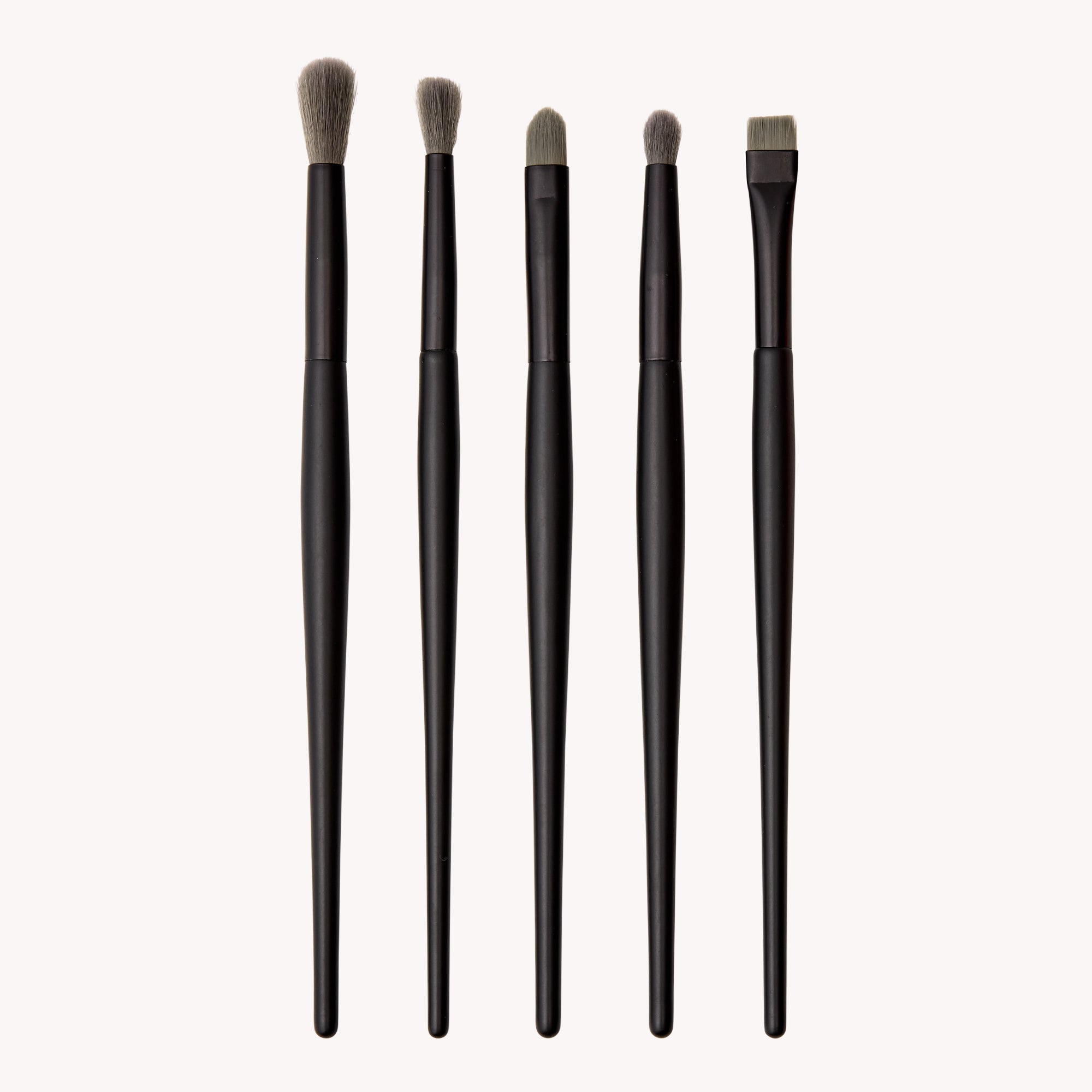 Set of five black makeup brushes with bristle heads on a white background