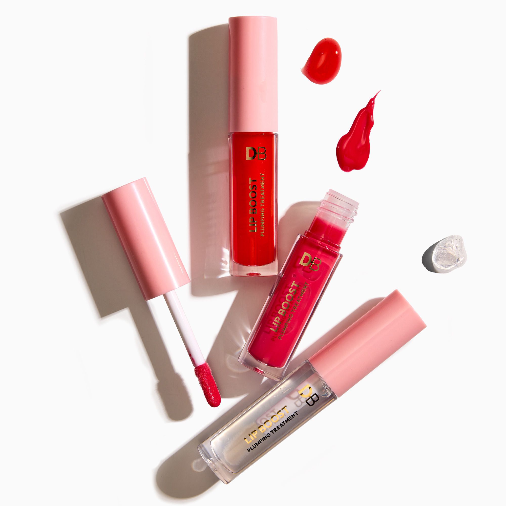 Red lip gloss with pink applicators on a white background