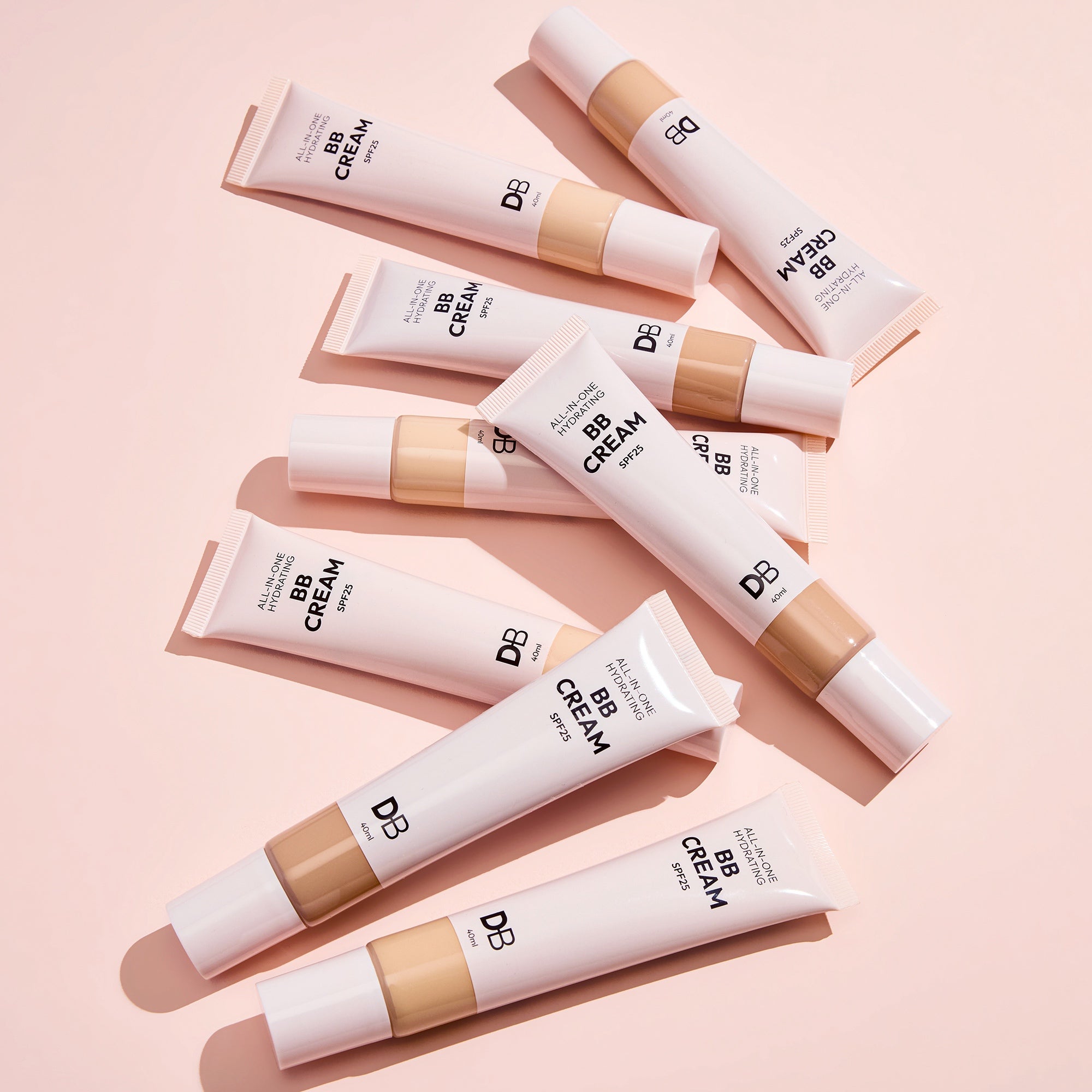 Multiple tubes of BB cream arranged on a pink background