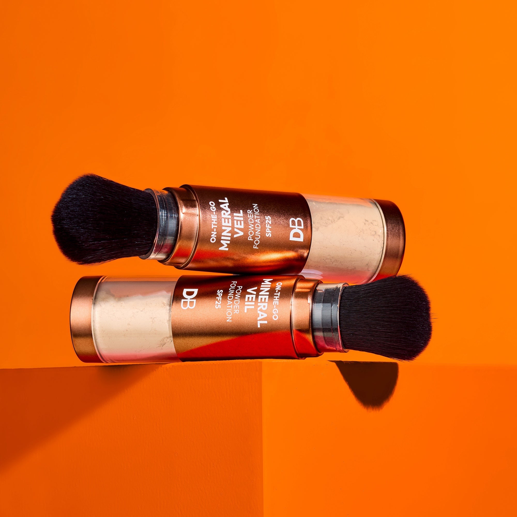 Two makeup products with brushes on an orange background
