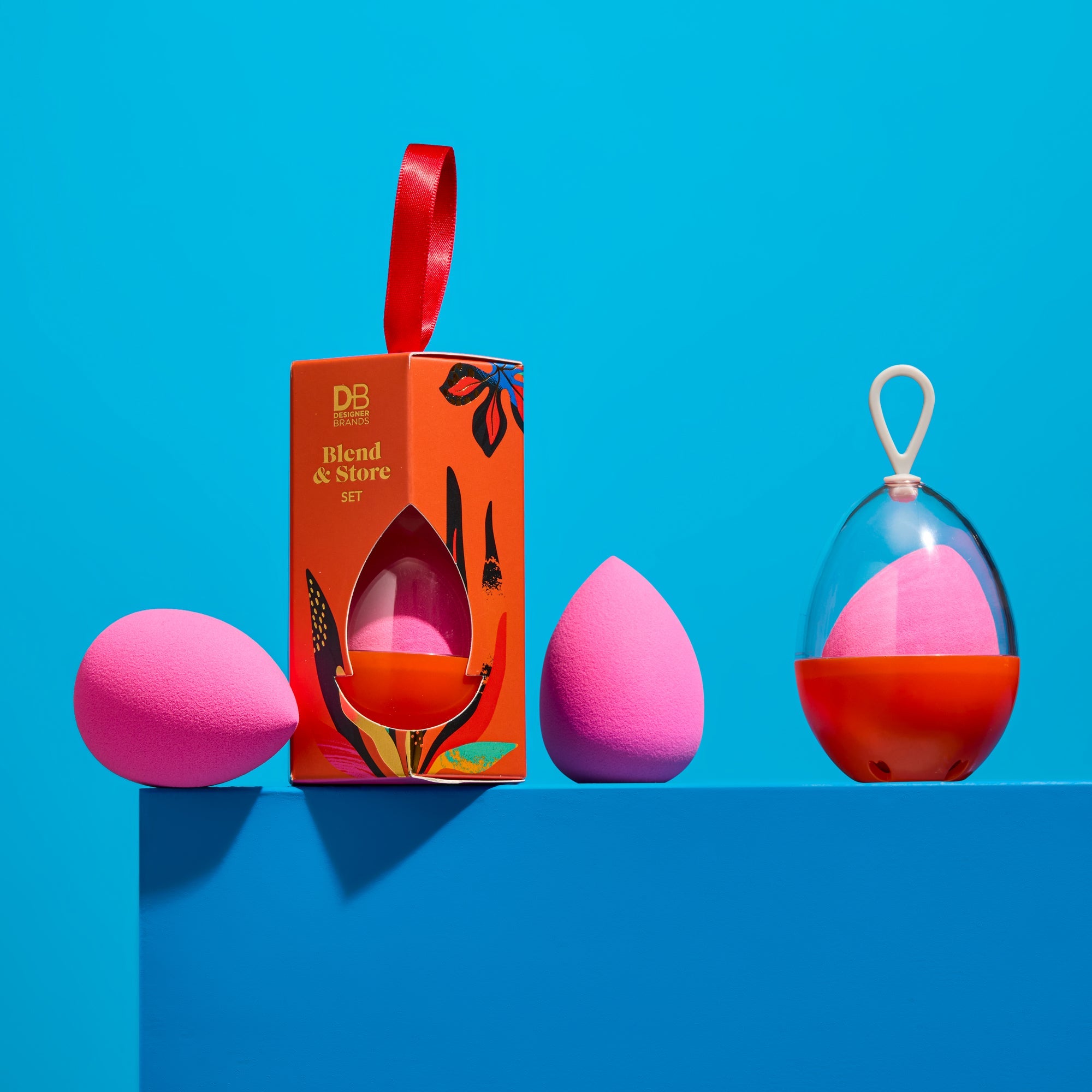 Pink and red beauty blender set with packaging on a blue background