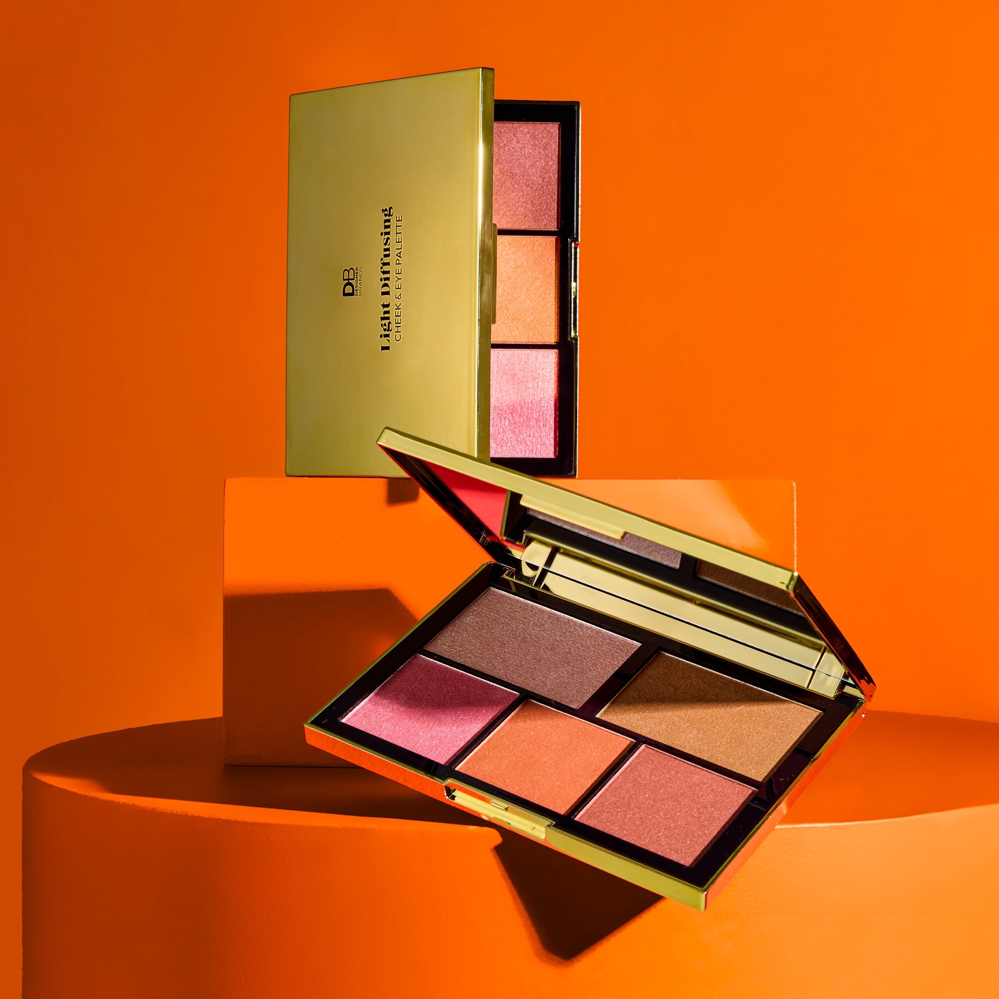 Makeup palette with pink and orange shades on an orange background
