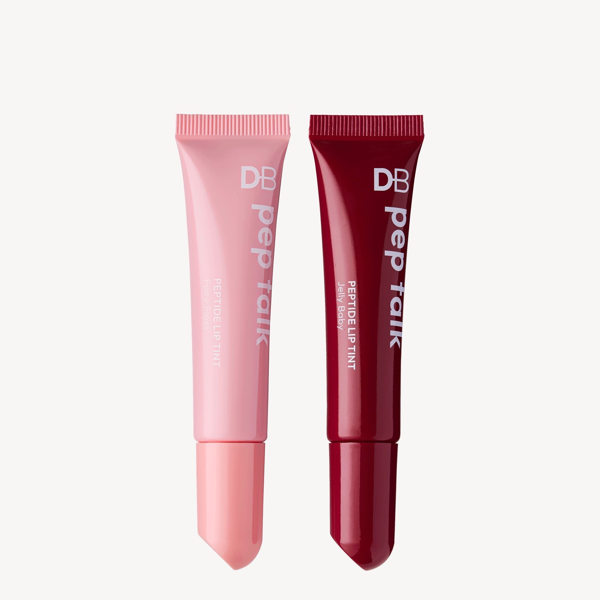 Two tubes of DB Pep Talk peptide lip tint, one light pink, one deep red, with white lettering, on a plain background.