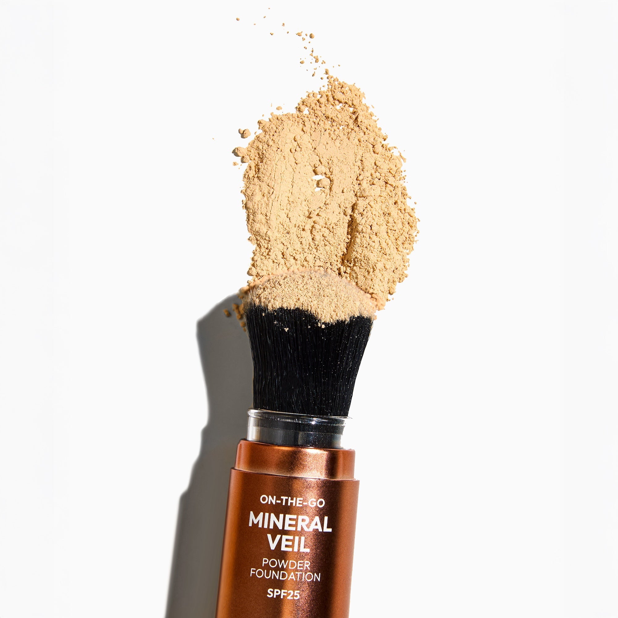 Mineral veil powder foundation with a brush on a white background