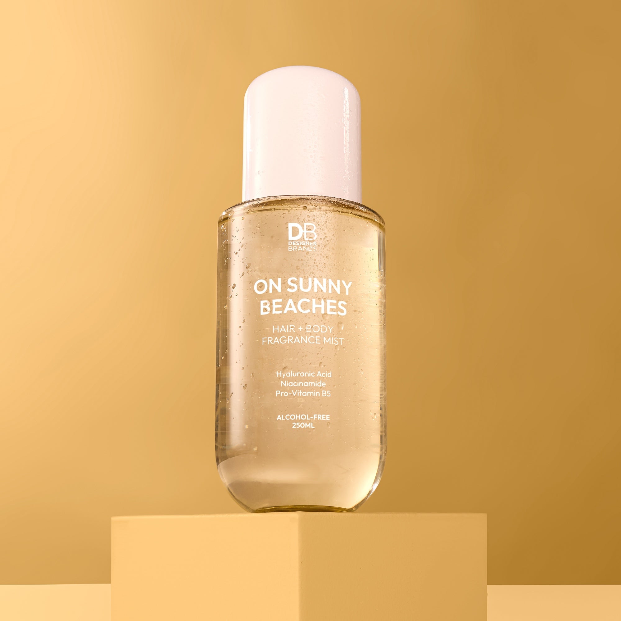 Bottle of 'On Sunny Beaches' fragrance mist on a gold background